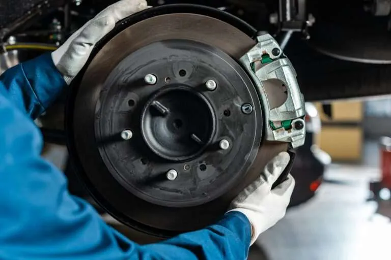 Technician fitting a brake caliper over a rotor at Anywhere Automotive
