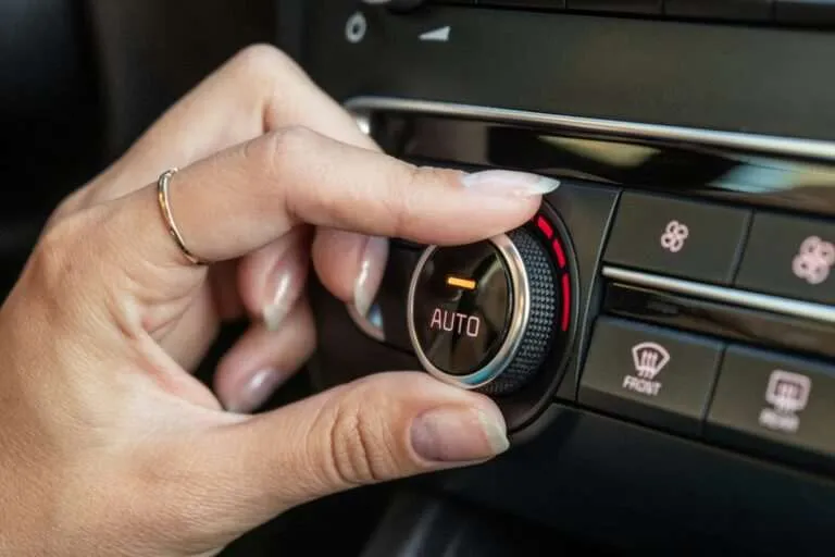 Hand adjusting the climate control dial on a car dashboard