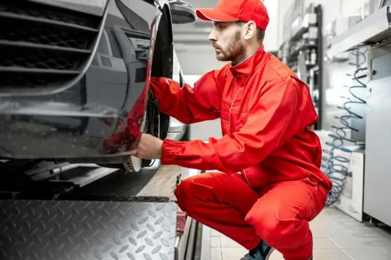 Mechanic kneeling beside a vehicle wheel during a fleet inspection