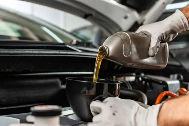 Technician pouring fresh motor oil into an engine through a funnel