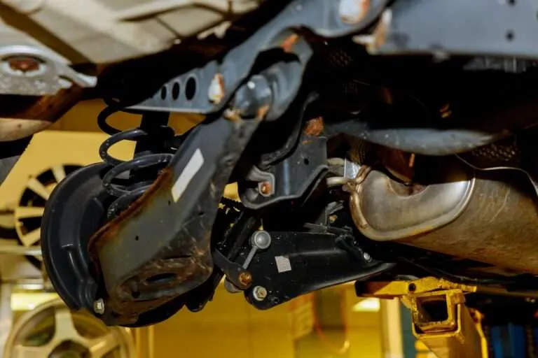 Underside view of a car suspension with control arm and coil spring
