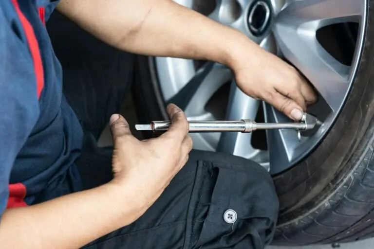 Technician tightening wheel lug nuts on a car tire